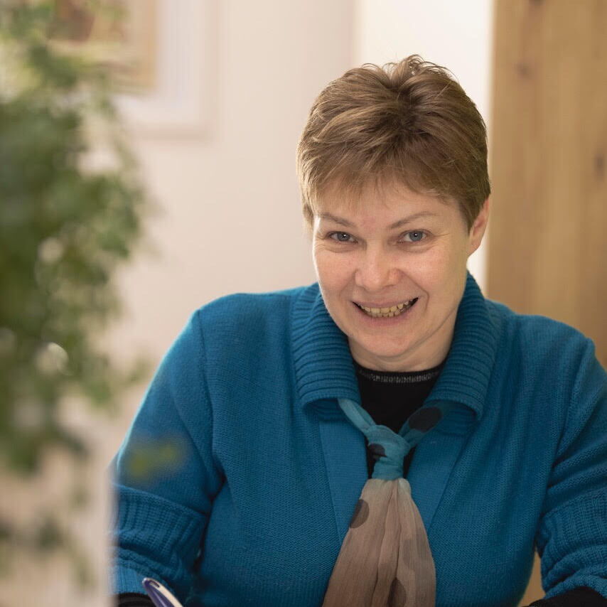 Ein Bild der Wahlärztin Gabriele Wesley, während sie etwas schreibt und in die Kamera schaut und lächelnd.