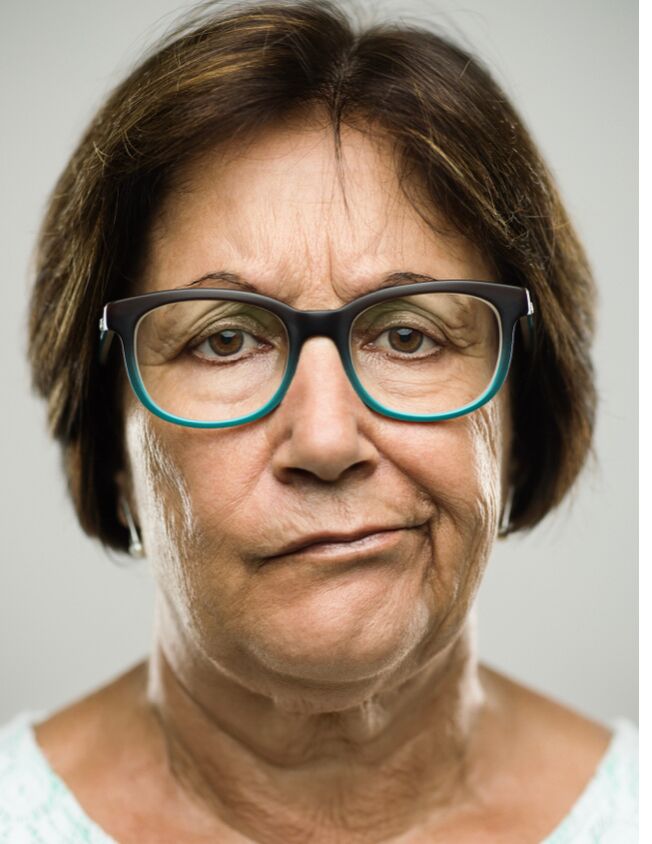 Ein Porträt einer Frau mit Brille die trüb in die Kamera schaut
