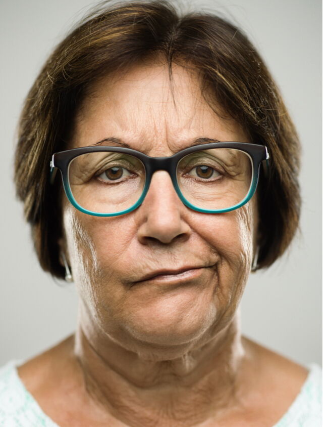 Ein Porträt einer Frau mit Brille die trüb in die Kamera schaut