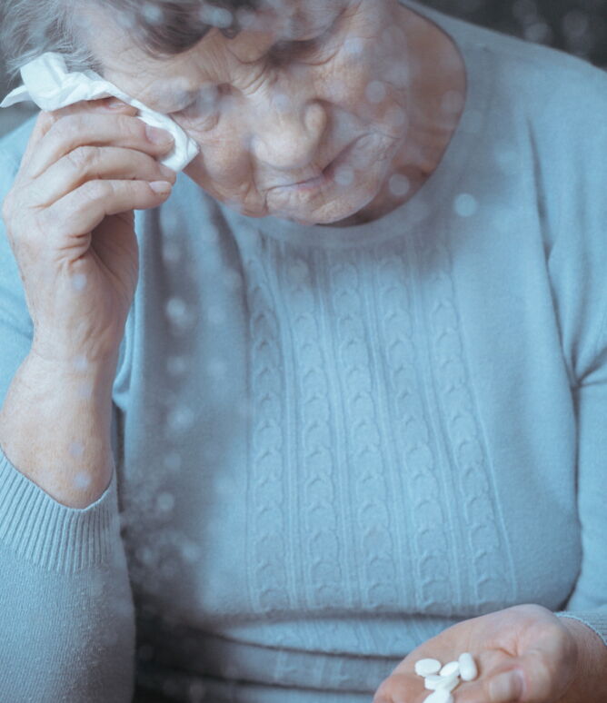 Ältere bedrückte Dame mit einer handvoll Tabletten