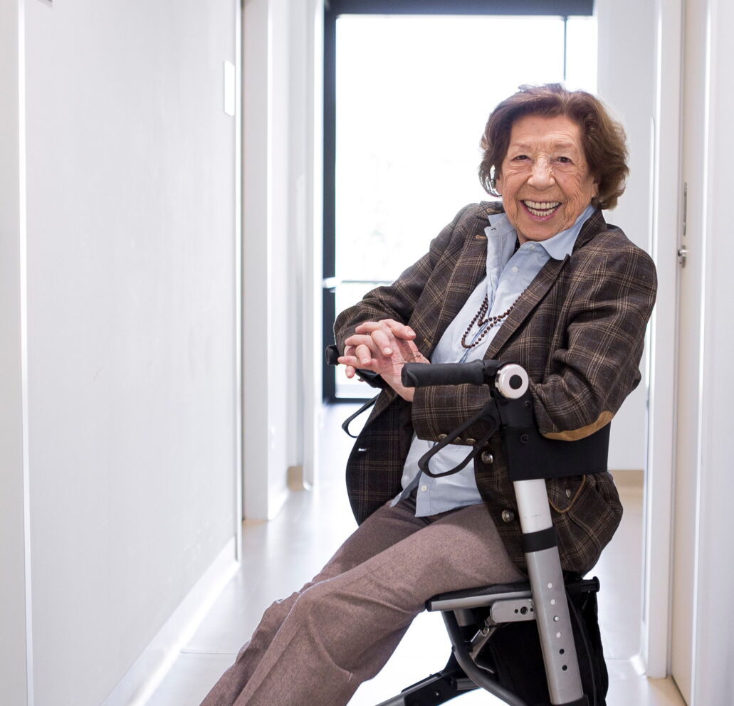 Ältere Dame in einem Rollator lachend in die Kamera