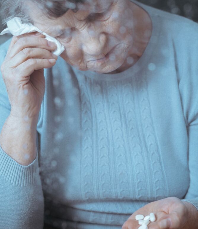 Ältere bedrückte Dame mit einer handvoll Tabletten